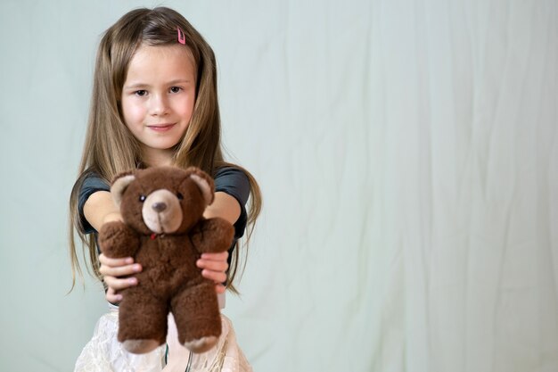 Pretty child girl playing with her teddy bear toy.