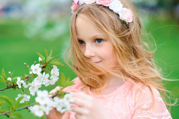 かわいい子の女の子の笑顔と庭の花、咲く木、チェリー、リンゴで遊んで。