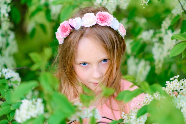 Pretty child girl smiling and playing in flowers of the garden, blooming trees, cherry, apples.