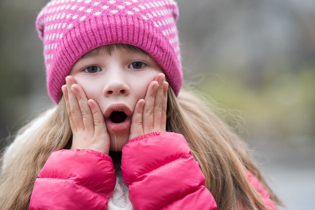 Pretty child girl in warm knitted winter clothes outdoors.