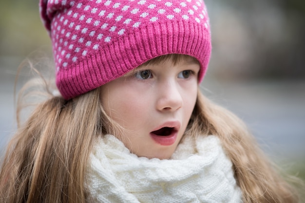 Pretty child girl in warm knitted winter clothes outdoors.