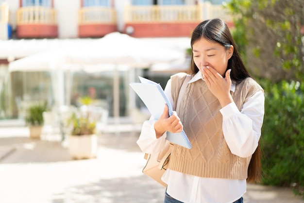 Pretty Chinese student woman at outdoors with surprise and shocked facial expression