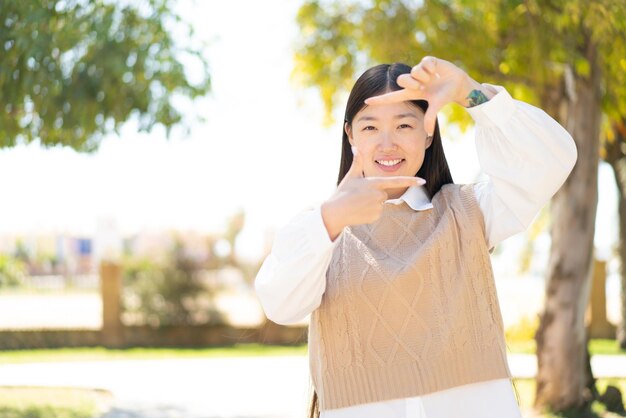 写真 屋外で顔のフレーミング シンボルに焦点を当てたかなり中国人の女性