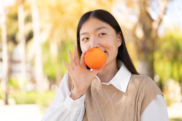 사진 오렌지를 들고 야외에서 예쁜 중국 여자