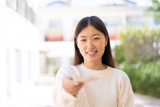 写真 屋外でたくさんのお金を取るかなりの中国人女性