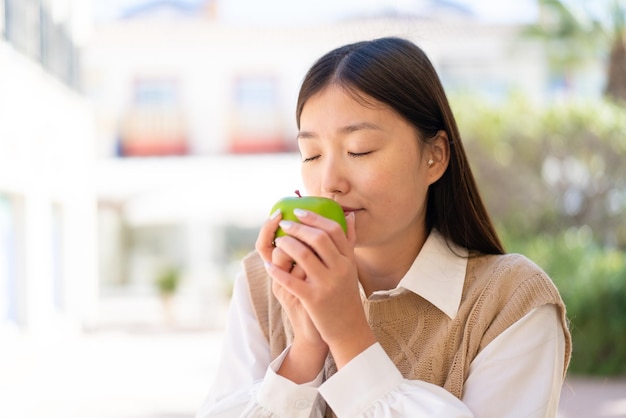 Pretty Chinese woman at outdoors holding an apple