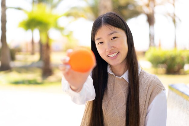 オレンジを保持している屋外でかなり中国の女性