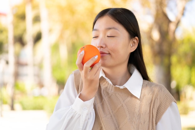 Pretty Chinese woman at outdoors holding an orange