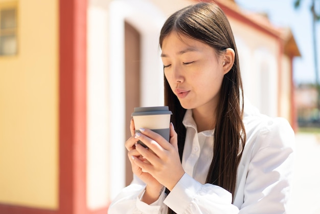 テイクアウトのコーヒーを保持している屋外でかなり中国の女性