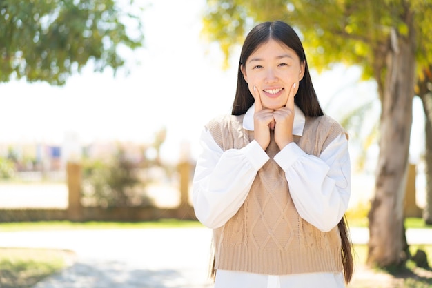 Pretty Chinese woman at outdoors smiling with a happy and pleasant expression