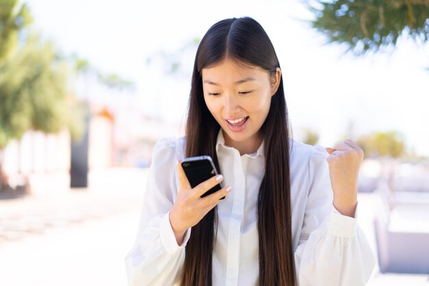 Pretty Chinese woman at outdoors surprised and sending a message