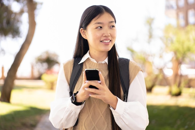 Pretty Chinese woman at outdoors using mobile phone