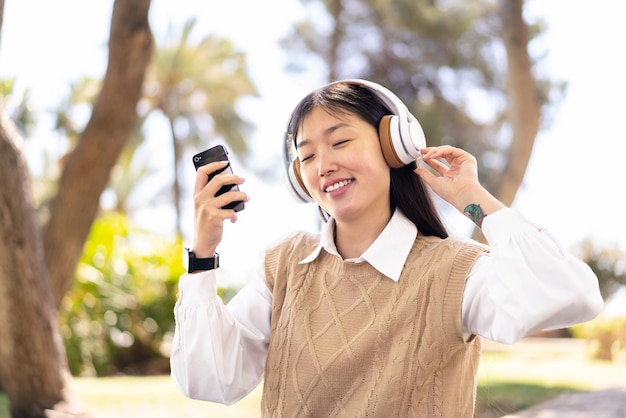 Pretty Chinese woman at outdoors using mobile phone