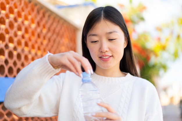 Bella donna cinese con una bottiglia d'acqua all'aperto