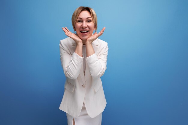 Pretty confident wellgroomed young blond business leader woman in a white jacket and dress smiling