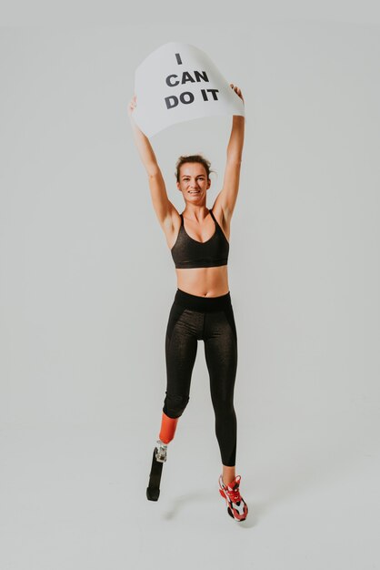 Pretty and confident woman with leg disability posing with I can do it board