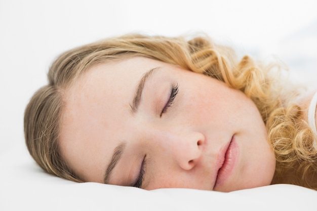 Pretty content blonde lying in bed resting with closed eyes