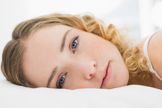 Pretty content blonde lying in bed resting