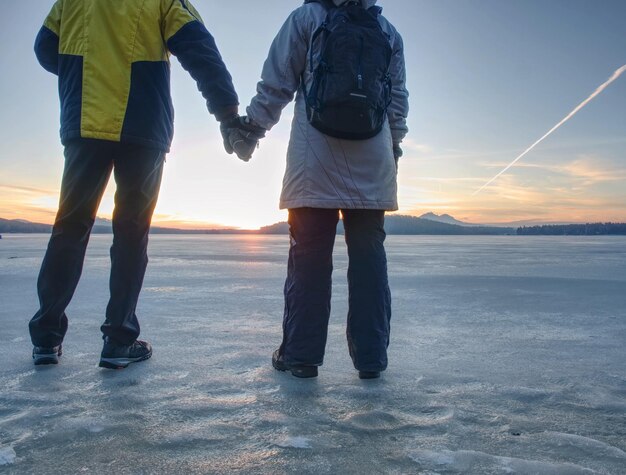 Photo pretty couple have fun on beach winter walk at frozen sea ice cover of lagoon with footprints