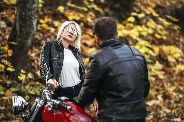 Pretty couple near red motorcycle on the road in the forest  