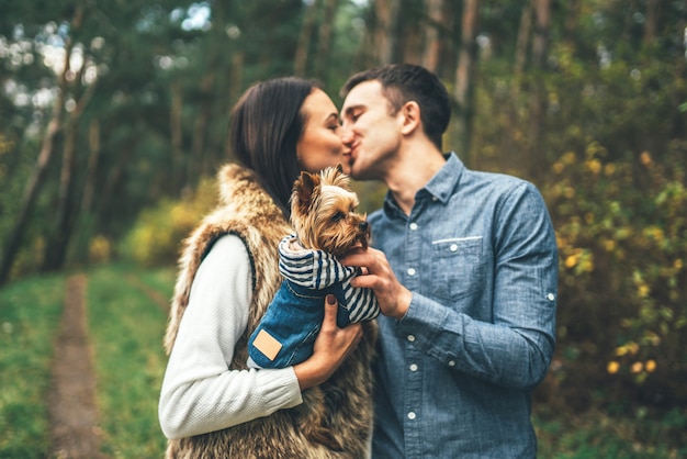 Foto coppie graziose con il piccolo yorkshire terrier che cammina nella foresta.