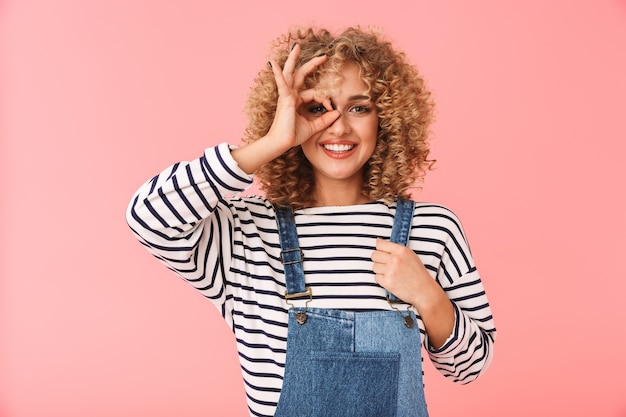 pretty curly woman 20s smiling and showing ok sign