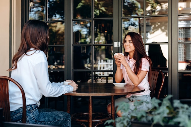 Pretty cute brunette talking to each other while sitting at the table