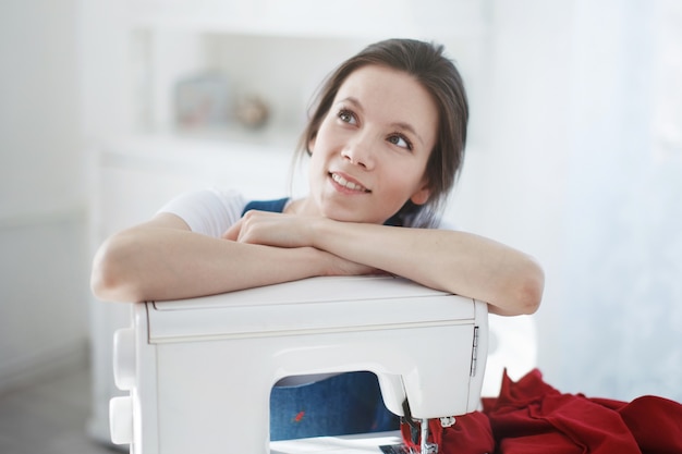 Pretty Cute young girl in a blue dress sews on a sewing machine.