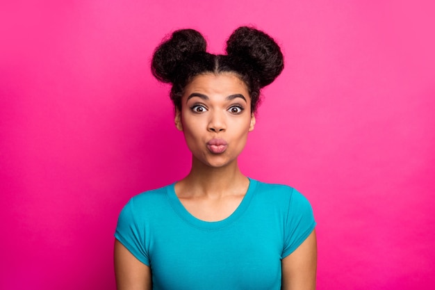 Pretty dark skin lady with two buns hairdo send air kiss on pink background