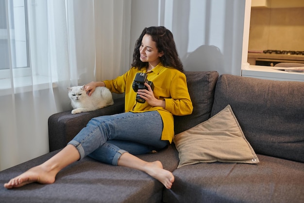 Pretty darkhaired woman with camera stroking her white cat