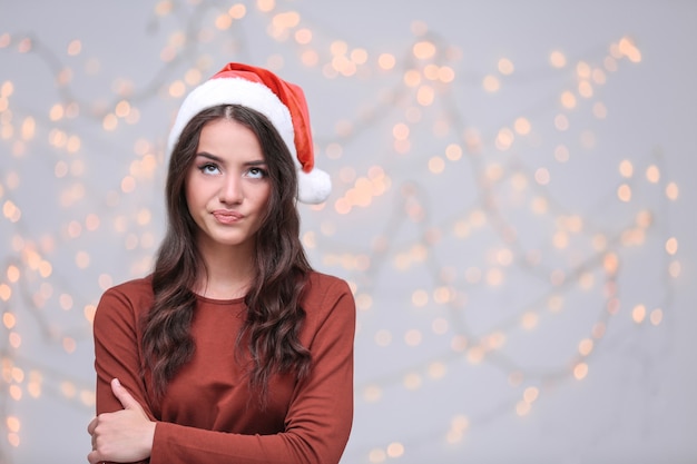 Pretty emotional lady in Christmas hat on blurred background
