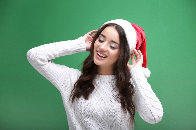 色の背景にクリスマス帽子のかなり感情的な女性