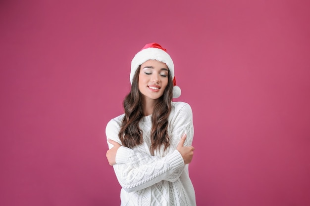 Pretty emotional lady in Christmas hat on color background