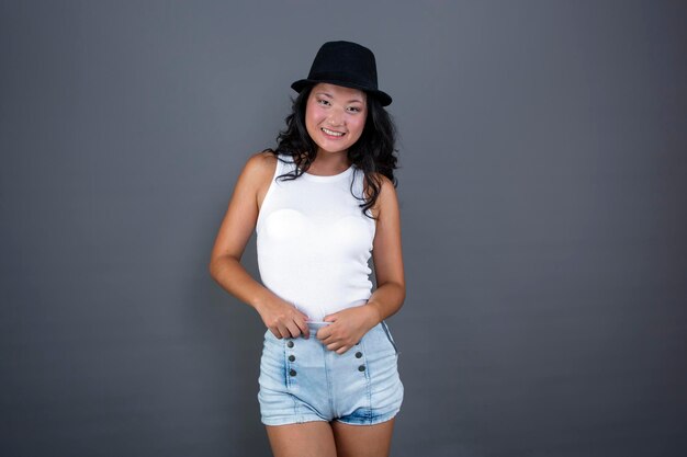 Pretty ethnic asian girl posing in tank top shorts and hat