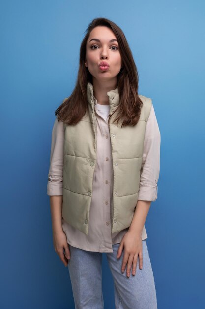 Pretty european brunette young woman in vest and shirt on studio background