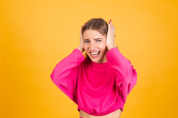 Pretty european woman in pink blouse on yellow wall