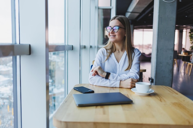 Pretty European young business woman in a coffee shop Wearing an elegant casual suit and sitting with a laptop in a public cafe