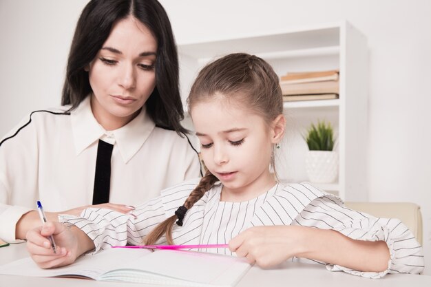 Pretty family concept. Mom and daughter sitting together and studying at home.