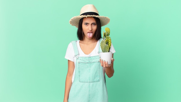 Bella contadina che si sente disgustata e irritata e fa la linguaccia e tiene in mano un cactus