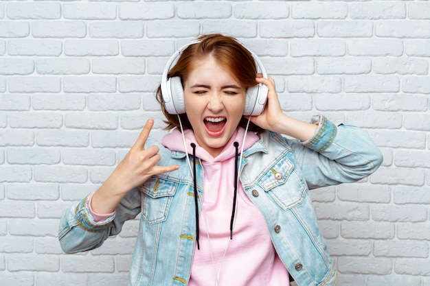Pretty fashion cool girl listening to music in headphones