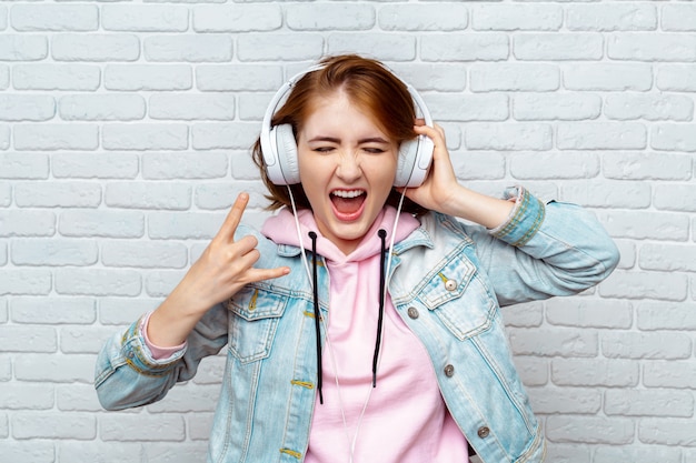 Ragazza graziosa di modo che ascolta la musica in cuffie