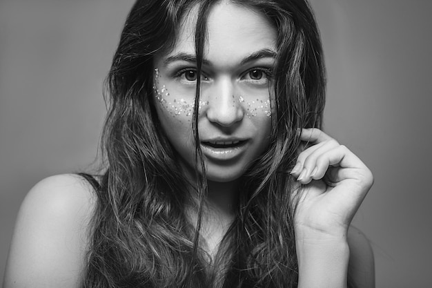 Pretty fashion model Young female with glitter freckles Flirty facial expression Focused eyes Black and white