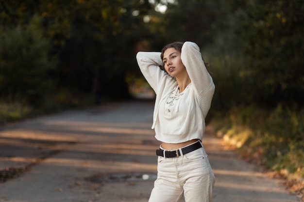 Pretty fashionable woman model with curly hair in vintage knitted sweater walks in the park outdoors