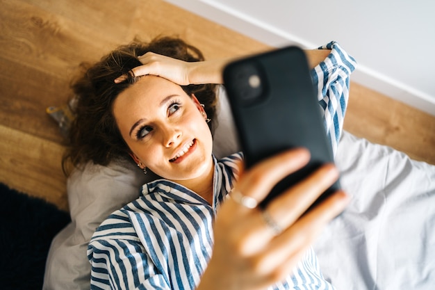 pretty female creating content for social media Influencer in bedroom relaxed having video chat