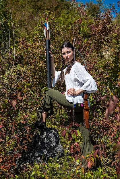 Pretty female hunter with bow plays as native American Indian