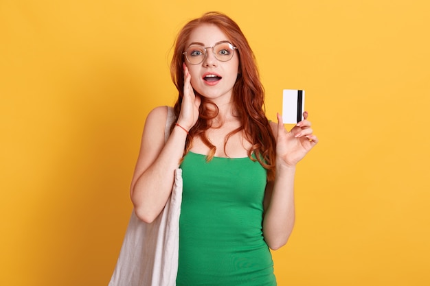 Pretty female standing against yellow wall