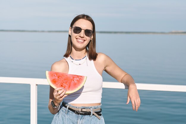 Pretty female in sunglasses holding big slice of watermelon