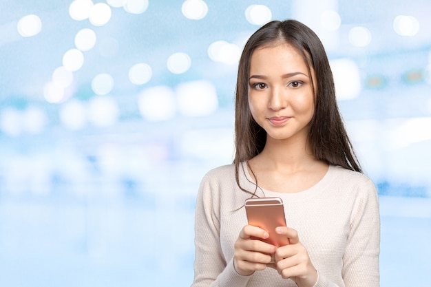 Adolescente femminile grazioso che per mezzo dello smartphone