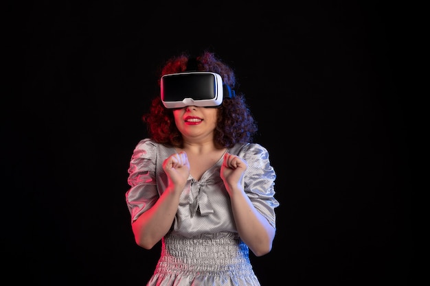 Pretty female wearing virtual reality headset on dark surface