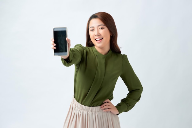 Pretty female with shining smile shows smart phone with blank copy screen for your advertisment